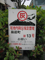A common sign on the sidewalks of Kagoshima City, instructing residents and shopowners to bag the volcano ash they sweep up, and leave it by the sign for collection
