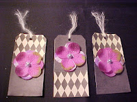 6 of 6 - These tags are covered with scrapbook papers. I have added fabric flower petals with a vintage pearl as the center. Of course, I had to put alittle glitter on it too! Size is 5 1/4" X 2 5/8" and are blank on the back.